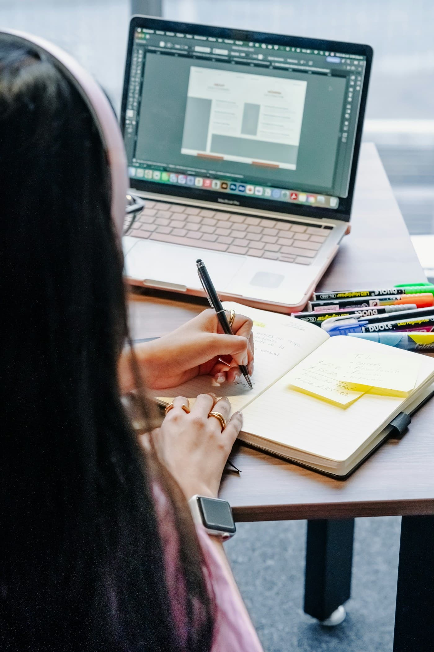 A professional planning focused work beside a laptop and notebook
